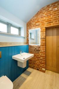 a bathroom with a white sink and a brick wall at Alde Bay Farm - Oyster Catcher in Aldeburgh