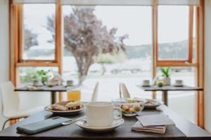 una mesa con platos de comida y una taza de café en Hostería El Coirón en Esquel