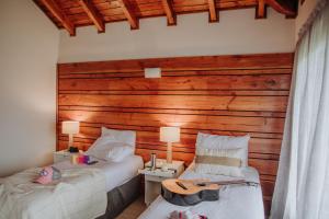1 dormitorio con 2 camas y pared de madera en Hostería El Coirón en Esquel