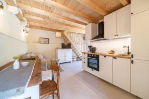 una cucina con armadi bianchi e soffitto in legno di Stone bridge cottage a Dol
