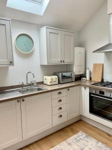 a kitchen with white cabinets and a clock on the wall at 19a Brooks Road in Street