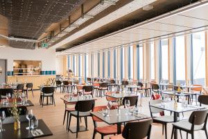 Afterwork Hotel في Etoy: غرفة طعام بها طاولات وكراسي ونوافذ