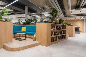 Afterwork Hotel في Etoy: مكتبة بها أريكة زرقاء ورفوف كتب