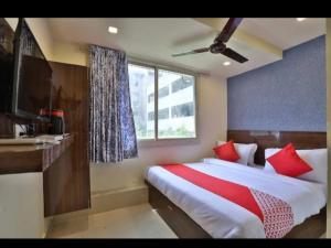 a bedroom with a bed with red pillows and a window at Hotel Skyland in Ahmedabad