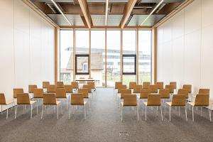 a room with chairs and tables and large windows at Afterwork Hotel in Etoy