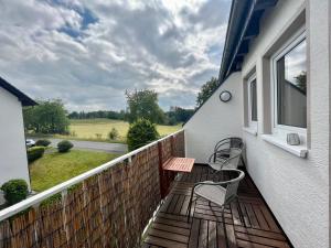 a balcony with two chairs and a table and a window at favstay Industrialstyle 2-Zimmer 60qm mit Balkon, Panarbora Fernblick, 55" TV & Netflix, 55Mbit WLAN, Parkplatz in Waldbröl