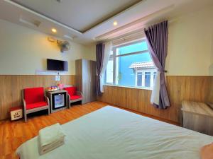 1 dormitorio con 1 cama, 2 sillas rojas y ventana en Dalat Holiday Hotel, en Da Lat