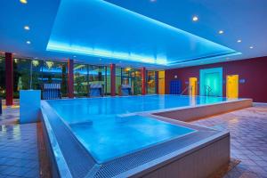 a large swimming pool in a building with a blue light at Dorint Hotel & Sportresort Arnsberg/Sauerland in Neheim-Hüsten