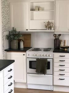 a kitchen with a white stove and white cabinets at Mysigt hus med utsikt över Östgötaslätten in Vikingstad