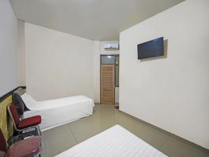 a room with two beds and a tv on a wall at OYO 92230 Penginapan Metro Parepare in Parepare