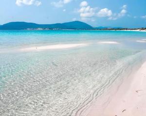 a beach with clear water and mountains in the background at Trilocale a 150 metri Spiaggia Alghero in Alghero