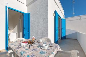 una mesa con sillas blancas y una puerta azul en Residence Mare Azzurro by BarbarHouse, en Porto Cesareo