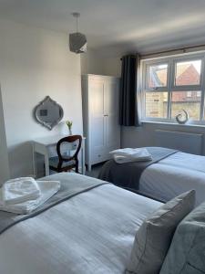 a bedroom with two beds and a desk and a window at The Old Dairy in Great Ayton