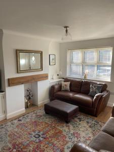 a living room with a brown leather couch and a rug at The Old Dairy in Great Ayton