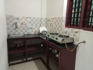 a small kitchen with a stove and a sink at Stylehomes The Farm House Inn (Heritage Resort) in Lokamaleswaram