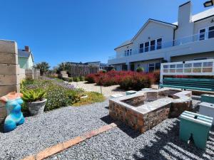 un patio trasero con una hoguera y un banco en Anchor's Rest, en Yzerfontein