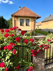 ein Haus mit roten Rosen auf einem Zaun in der Unterkunft AEDA chalupa in Liptovské Sliače