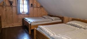 two beds in a room with wooden walls at Palčovka Huty - apartmán U Ondry a U Andělky in Huty