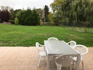 einem Tisch mit vier Stühlen und einem Grasfeld in der Unterkunft MAISON CHAMPAGNE, charmante maison au calme avec beau terrain in Saint-Germain