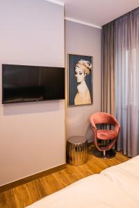 een kamer met een bed, een stoel en een televisie bij Teatro Suite & Rooms in Rijeka