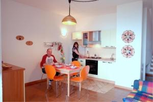een vrouw en een man aan een tafel in een keuken bij Primavera Apartments in Capo Testa