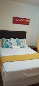 uma cama com almofadas e uma fotografia na parede em myStay Sandton em Joanesburgo