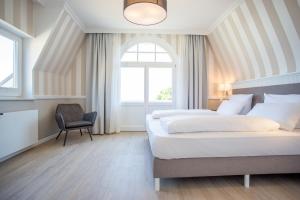 a bedroom with two beds and a chair and a window at Hotel Vier Jahreszeiten Kühlungsborn in Kühlungsborn