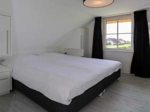 Un dormitorio con una gran cama blanca y una ventana en Beautiful villa with sauna and unobstructed view, on a holiday park in Friesland, en Delfstrahuizen