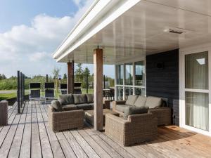 una casa con patio con sofás y sillas en Beautiful villa with sauna and unobstructed view, on a holiday park in Friesland, en Delfstrahuizen