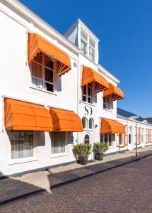 un bâtiment blanc avec des parasols orange dans une rue dans l'établissement Strandhotel Wilhelmina, à Domburg