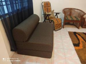 a brown couch sitting in a living room with chairs at R&R HOMESTAY in Simpang Renggam