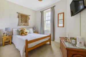a teddy bear sitting on a bed in a bedroom at Roscrea Bed & Breakfast in Bodmin