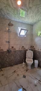 ein schmutziges Bad mit WC und Fenster in der Unterkunft Betegi Guest House in Mestia
