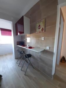 a kitchen with a counter and two stools in a room at Casa Terra Cota - Seixal in Amora