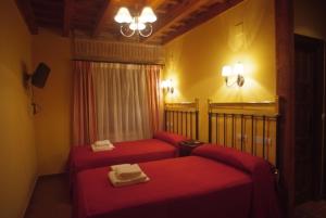 a room with two red beds in a room at La Casona de Doña Petra in Villarmentero de Campos