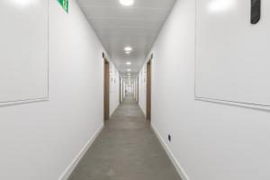 um corredor com paredes brancas e um longo corredor em micampus Madrid Sinesio Delgado Student Residence em Madrid