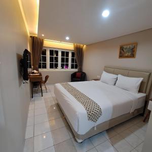 a bedroom with a bed and a desk and a television at Christine Hotel Jogja in Yogyakarta +8 photos