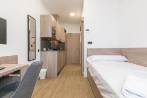 a bedroom with a bed and a desk and a kitchen at micampus Madrid Sinesio Delgado Student Residence in Madrid