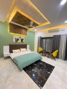 a bedroom with a bed and a table and yellow chairs at Book Rooms & Villa- Bairagarh Living Farm Stay in Shivpurī
