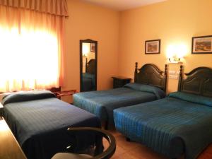 a hotel room with three beds and a mirror at Hostal Don Paco in Badajoz