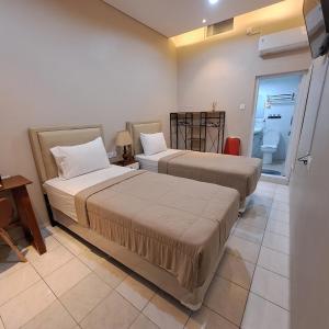 een kamer met 2 bedden, een bureau en een tafel bij Christine Hotel Jogja in Jetis