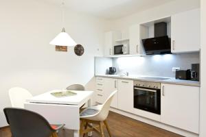 cocina con armarios blancos, mesa y sillas en Am Hafen1, en Röbel