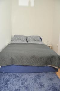 a bed with a gray comforter and a blue rug at Apartment with parking in the free garage in Sarajevo
