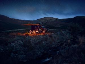 Eine Gruppe von Menschen, die auf einem Feld neben einem LKW sitzen in der Unterkunft Land Rover Defender Luxury Camper in Morpeth