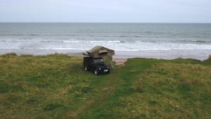 um camião estacionado na praia perto do oceano em Land Rover Defender Luxury Camper em Morpeth