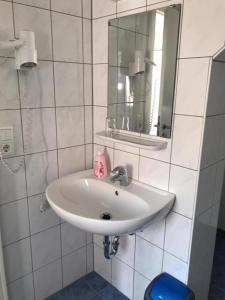 a white bathroom with a sink and a mirror at Pension Altstadt Garni in Bad Windsheim