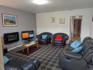 a living room with leather furniture and a flat screen tv at The Little Houses in Roybridge