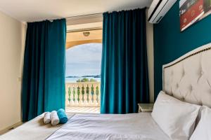 een slaapkamer met een bed en een raam met blauwe gordijnen bij Touristic Complex Hacienda Beach Apartments Sozopol in Sozopol