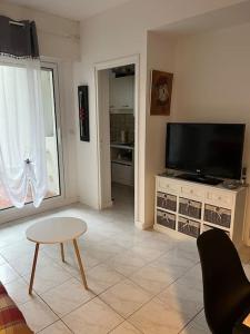 a living room with a flat screen tv and a table at Logement plein centre royan in Royan