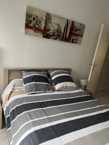 a bed with black and white striped sheets and pillows at Logement plein centre royan in Royan